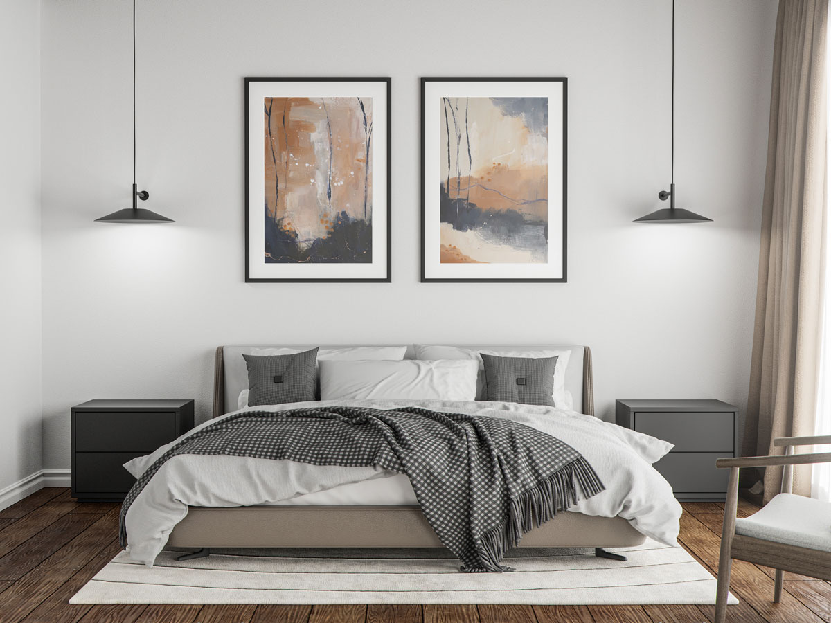abstract-landscape-painting1-2 Two abstract landscape paintings of bare trees in blue, cream and peach colors shown framed above a bed in a bedroom setting