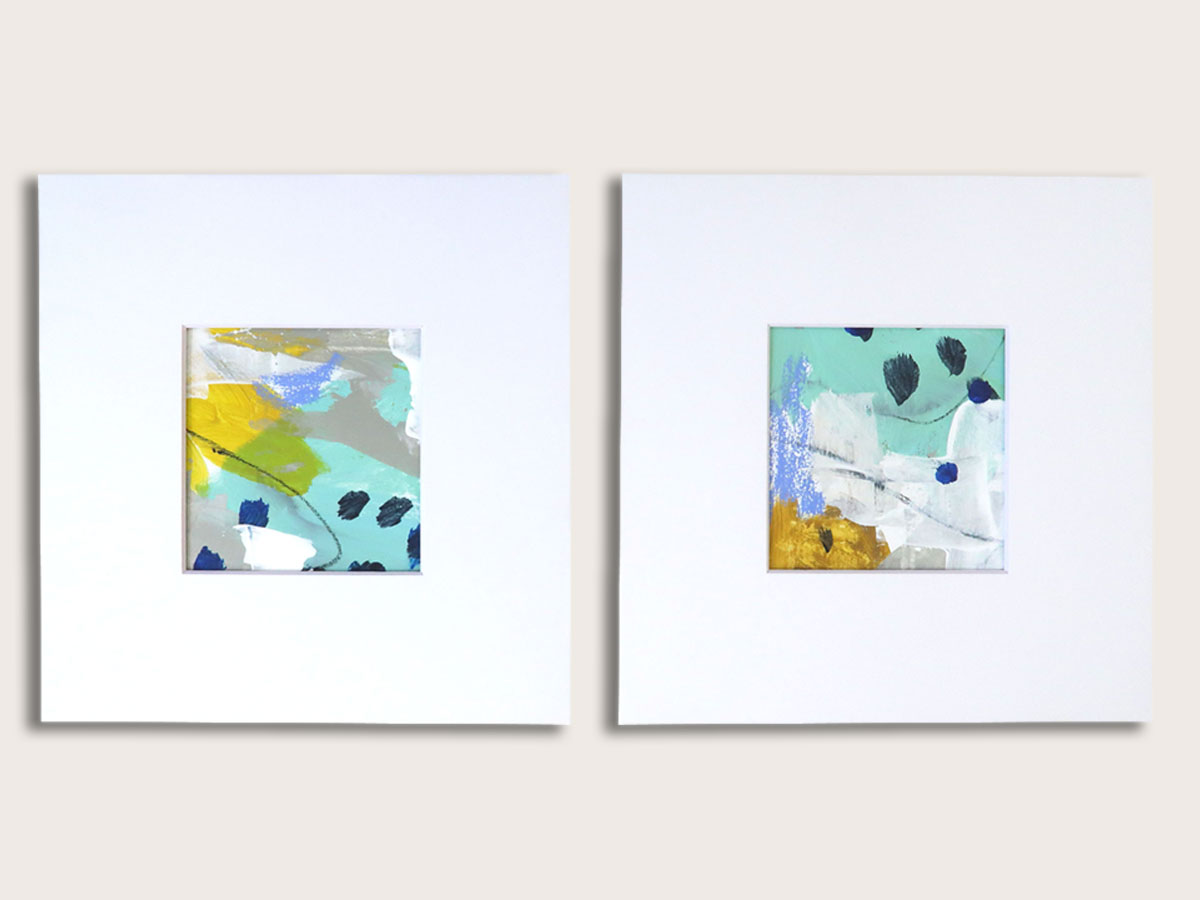 Set of two small, square abstract paintings in turquoise, yellow, gray and white shown with white mats