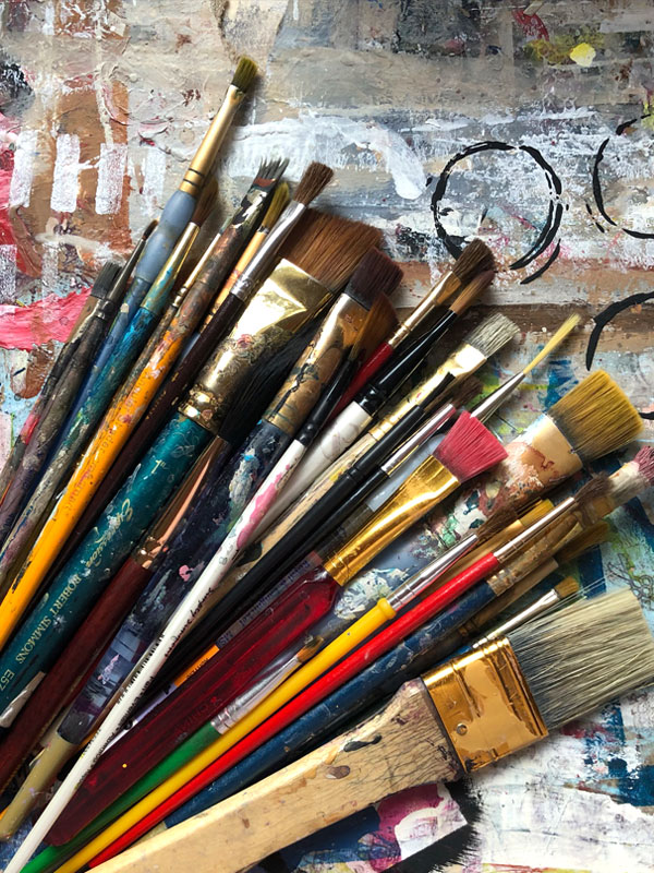 Paintbrushes laying on a painted background paper