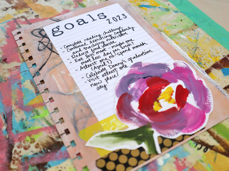 Example of how to decorate your planner using a custom yearly goals page made with a painted background, washi tape, and painted flower embellishment