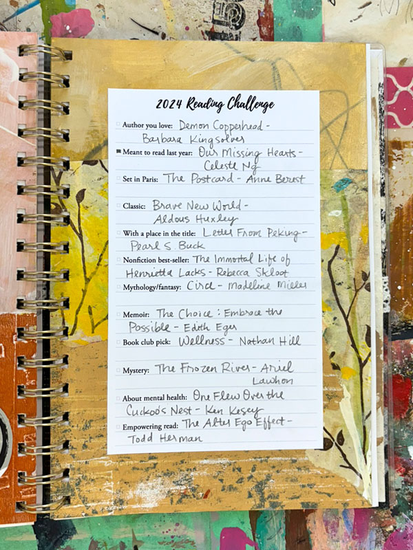 Reading challenge list on a painted artistic background in yellow added to a planner notebook